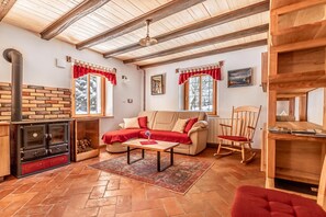 A cozy living room with a fireplace, a sofa, a rocking chair, and a dining table. - House By The Stream in Soca Valley (Kanal)