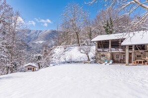 A snow-covered mountain landscape with a wooden cabin and a larger building with a sloped roof. - House By The Stream in Soca Valley (Kanal)