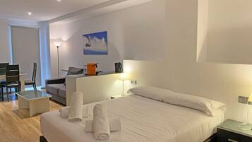 A hotel room with a bed, bedside tables, a desk, a chair, a lamp, and a painting on the wall.