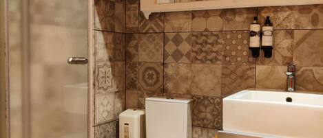 A bathroom with a toilet, a sink, and a shower area.