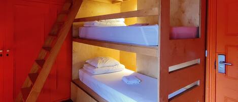 Un lit superposé avec une échelle en bois, un matelas blanc et un plancher en bois.