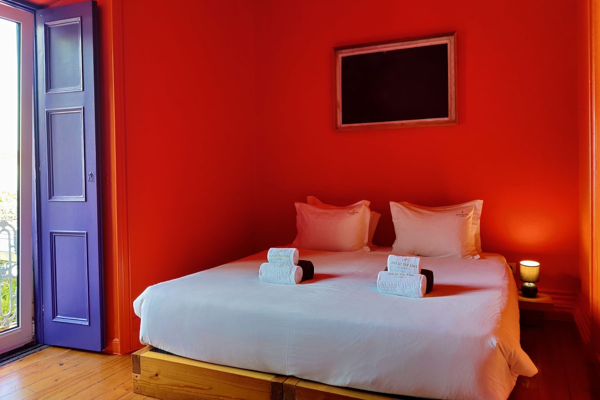 Een kamer met een bed, een deur en een wandlamp.