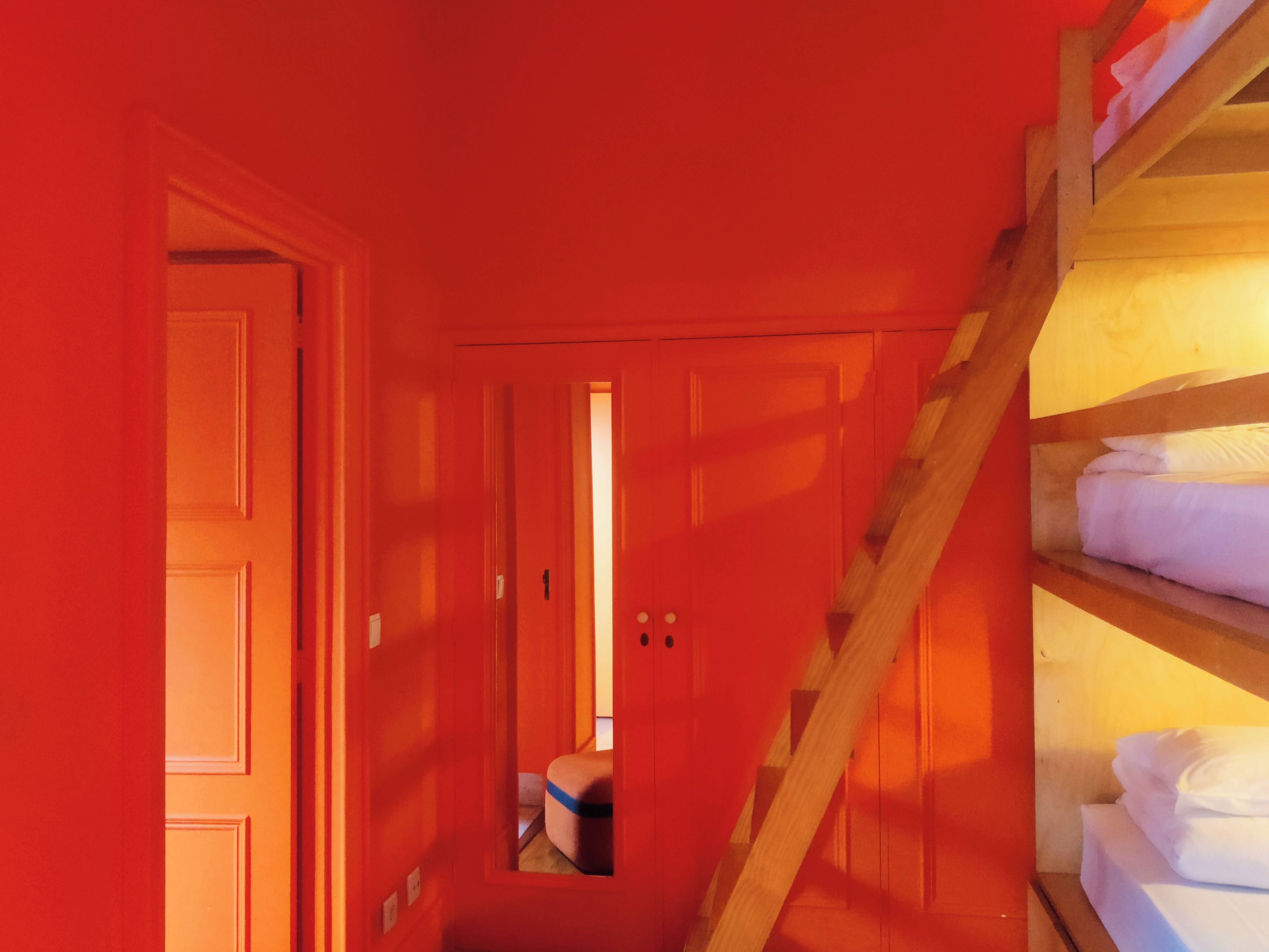 A narrow hallway with a wooden ladder leading to a bunk bed area.