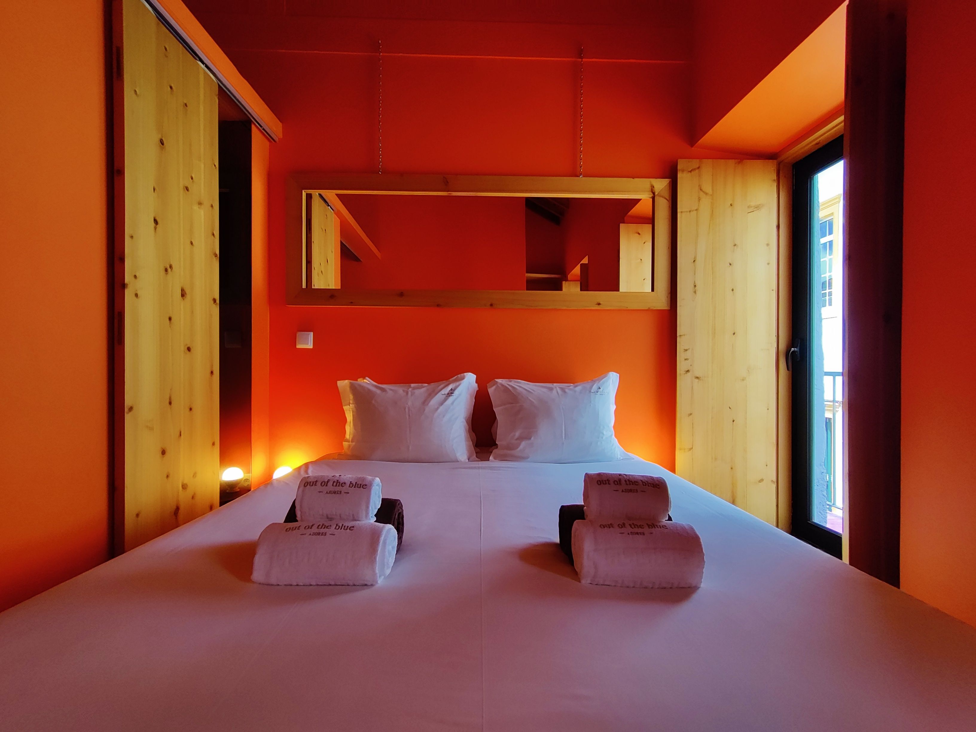 Ein Hotelzimmer mit einem großen Bett, zwei Kissen, einem Holzkopfteil, einem Spiegel und zwei Handtüchern mit Aufdruck.