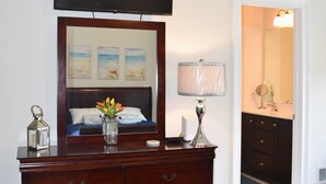 Un dormitorio con televisión, cómoda, lámpara y obras de arte en la pared.