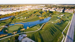 Vista aérea de un campo de golf con un lago, rodeado de edificios residenciales.
