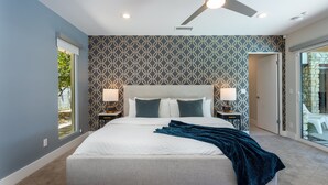 A bedroom with a bed, a ceiling fan, two bedside lamps, and a patterned wall.