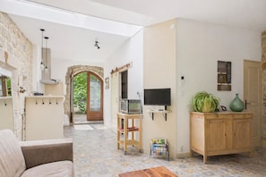 A living room with a sofa, TV, wooden cabinet, and a stone wall.