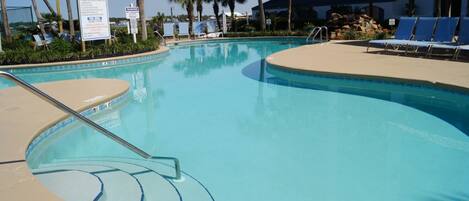 A swimming pool with lounge chairs and palm trees.
