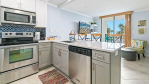 A modern kitchen with stainless steel appliances, a dishwasher, and a large island. - Gulf Shores Surf & Racquet Club 212A (Gulf Shores)