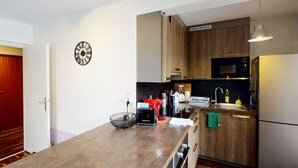 Una cocina moderna con armarios de madera, un refrigerador de acero inoxidable, un microondas y un lavamanos.