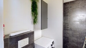 Un baño moderno con lavadora integrada, dispensador de toallas y un jardín vertical.