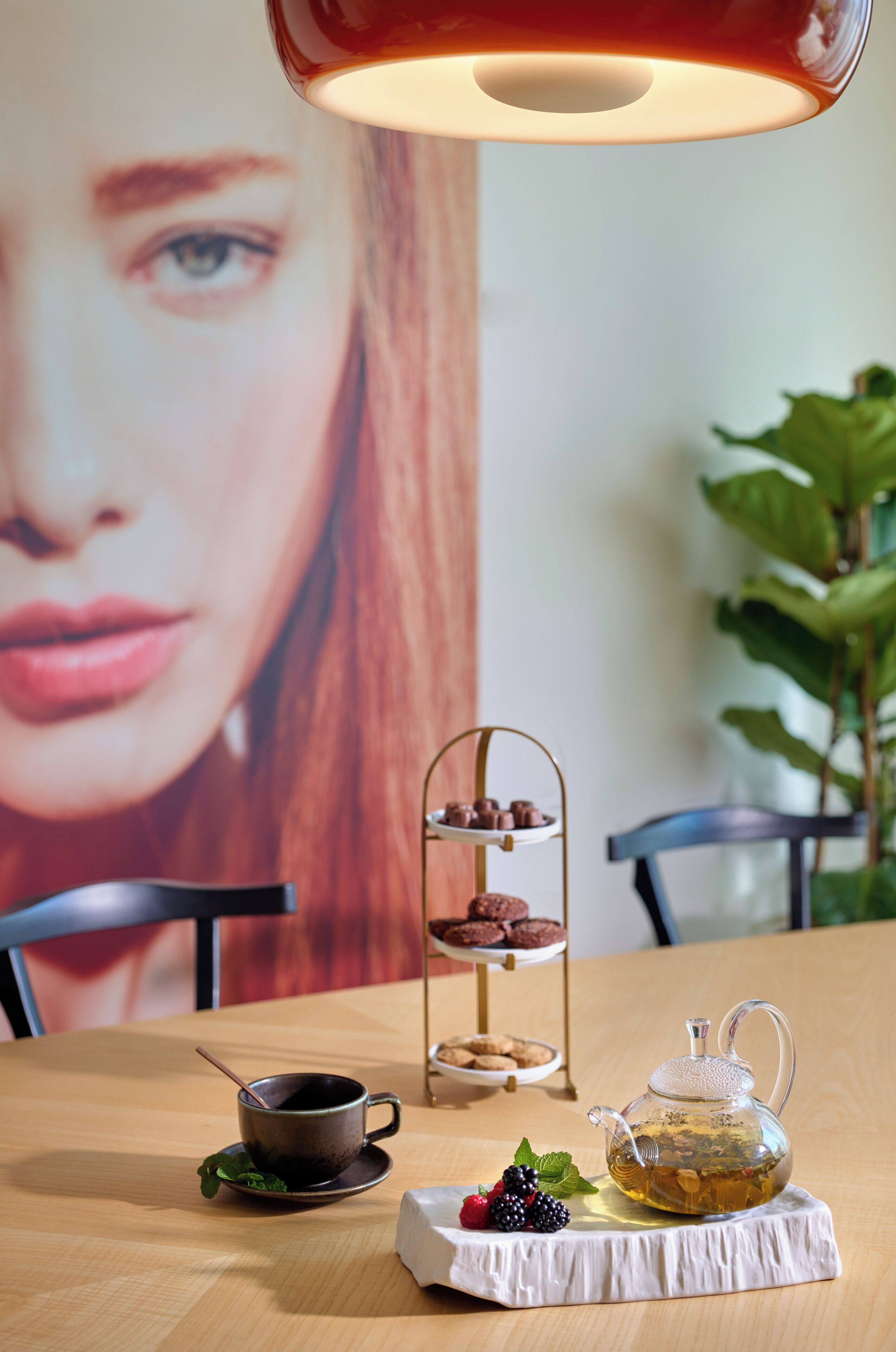 A table with a teapot, a cup, and a dessert stand with pastries.