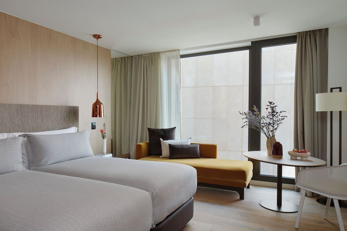 A modern hotel room with a large bed, a sofa, a small table, and a chair.