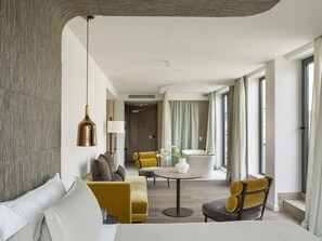 A modern hotel room with a sofa, armchair, and a round table with a vase of flowers. - ME Barcelona (Barcelona)
