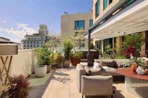 A rooftop terrace with outdoor seating, potted plants, and a view of a cityscape. - ME Barcelona (Barcelona)