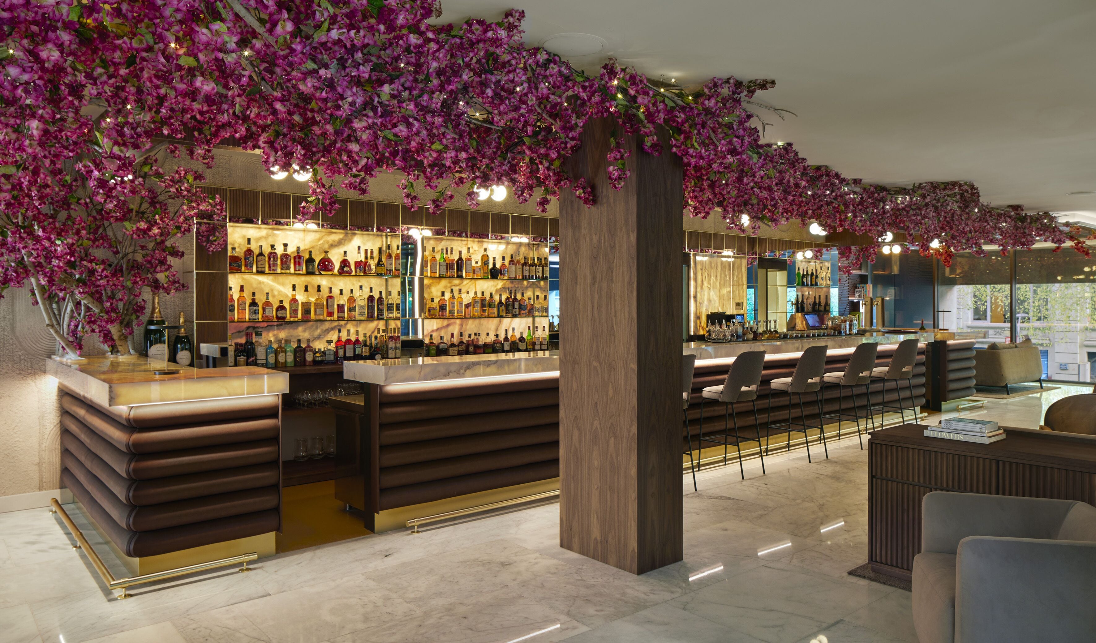 A bar area with a marble countertop, multiple liquor bottles, and bar stools.