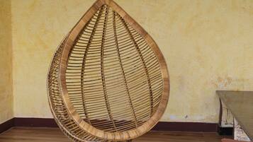 A wicker hanging chair in a room with wooden flooring and a textured wall.