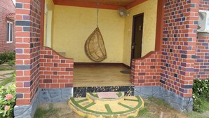 Un edificio de ladrillo con un porche de madera, una hamaca colgante y una puerta.