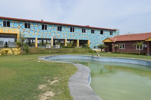 A building with a geometric facade, a swimming pool, and a grassy area.