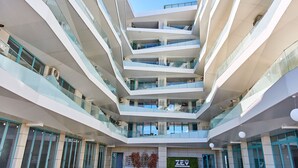 A multi-level atrium with glass railings and a central open space. - Apartament Alma Zev (Mamaia-Sat)