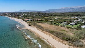 Una cittadina costiera con una spiaggia, case e montagne sullo sfondo.