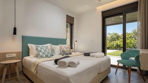 Camera d'hotel moderna con un letto grande, un tavolino, una sedia e vista sul verde dalla finestra.