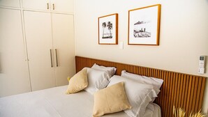 A neatly made bed with a wooden headboard, two framed pictures on the wall, and a wardrobe with a handle. - Penthouse Overlooking Ipanema Beach Vsc2 (Rio de Janeiro)