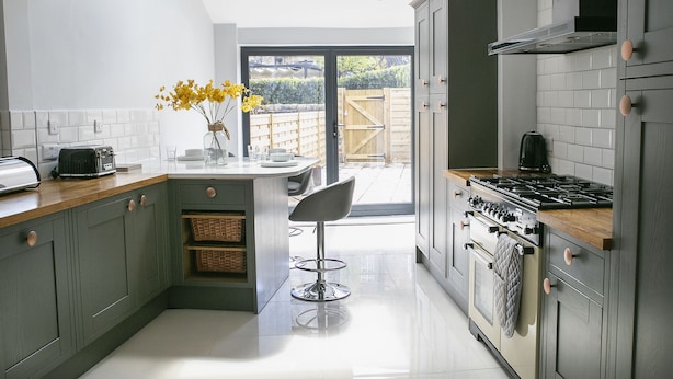 A modern kitchen with a central island, a stove, and a dining area with a chair. - Deluxe 4 bedroom house (Harrogate)