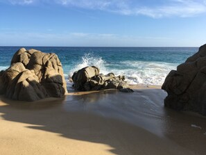 Une plage avec de gros rochers et des vagues qui déferlent sur le rivage.