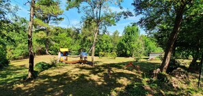 Een camping met een hangmat, speeltoestel en een kleine schuur.