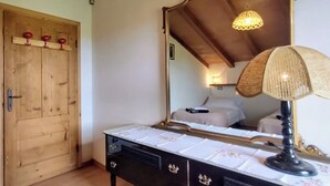 Et soveværelse med en trædør, et spejl, et sengebord med lampe og en seng med sengegavl.