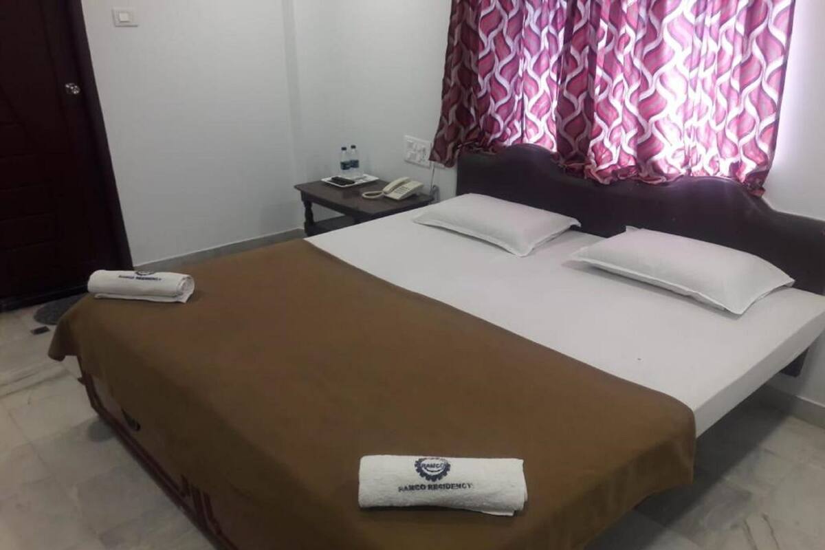 A hotel room with a bed, a nightstand, a telephone, and a water bottle.