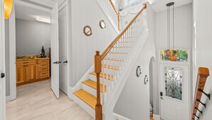 Una escalera de madera con barandillas blancas que lleva a un rellano con una puerta de cristal.