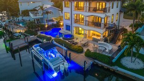 Un hotel de varios pisos con piscina, zona de estar al aire libre y un muelle con un barco.
