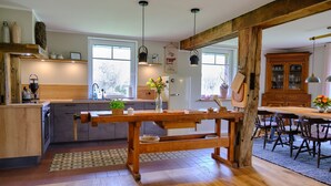 Une cuisine spacieuse dotée de meubles en bois, d’un îlot central et de luminaires suspendus.
