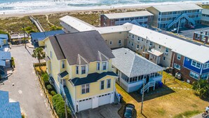 Zona residencial costera con un edificio grande de varios pisos que cuenta con garaje, porche cubierto y vistas a la playa.