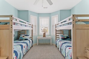 A room with bunk beds, a desk, and a window with blinds. - Sleeping Lady | Spacious, Oceanfront, Direct Beach Access (Carolina Beach)