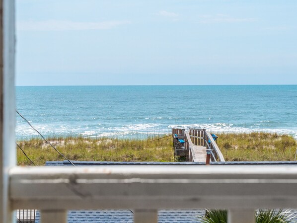 A view of the ocean from a balcony with a wooden deck and chairs. - Sleeping Lady | Spacious, Oceanfront, Direct Beach Access (Carolina Beach)