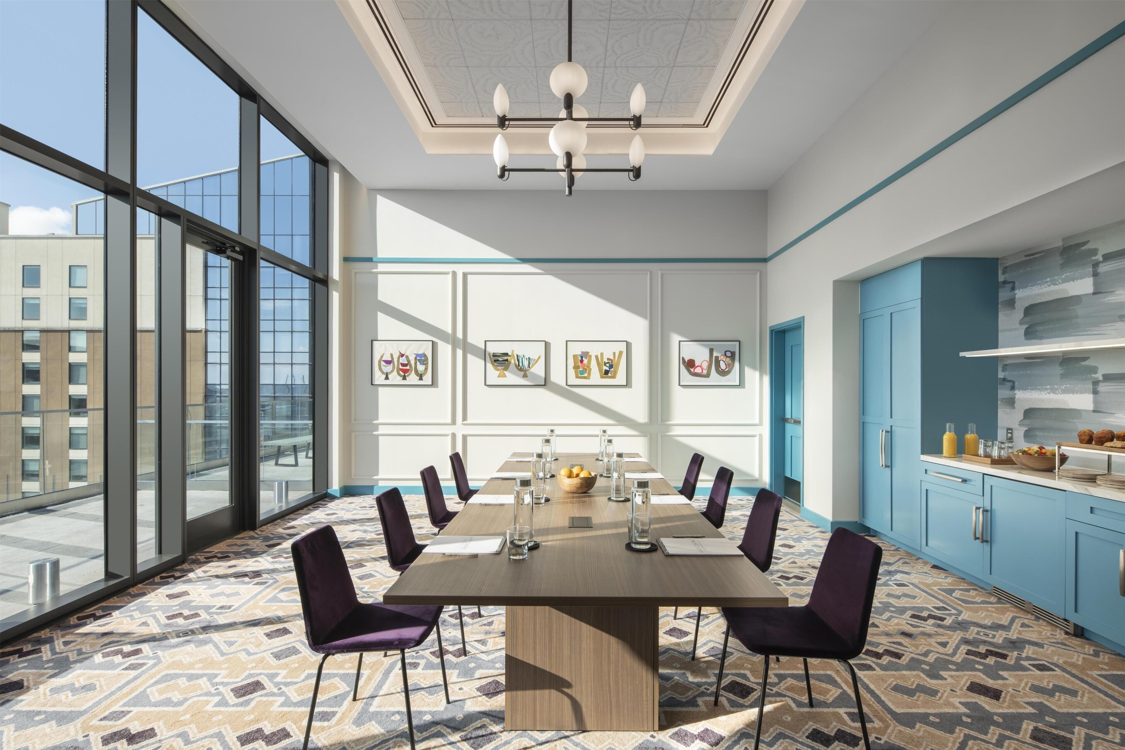 Une salle de conférence dotée d’une grande table, de chaises et offrant une vue sur la ville grâce à de larges fenêtres.
