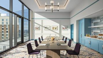 A conference room with a large table, chairs, and a city view through large windows.