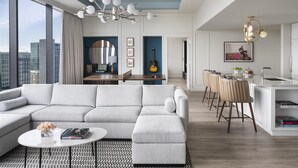 Una sala de estar moderna con un sofá seccional, una zona de comedor con barra y una cocina con taburete.