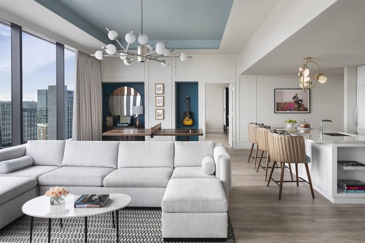 A modern living room with a sectional sofa, a dining area with a bar, and a kitchen with a bar stool.