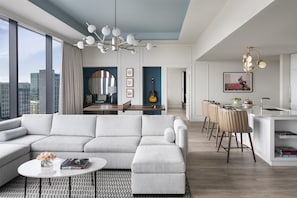 A modern living room with a sectional sofa, a dining area with a bar, and a kitchen with a bar stool. - Hyatt Centric Downtown Nashville (Nashville)