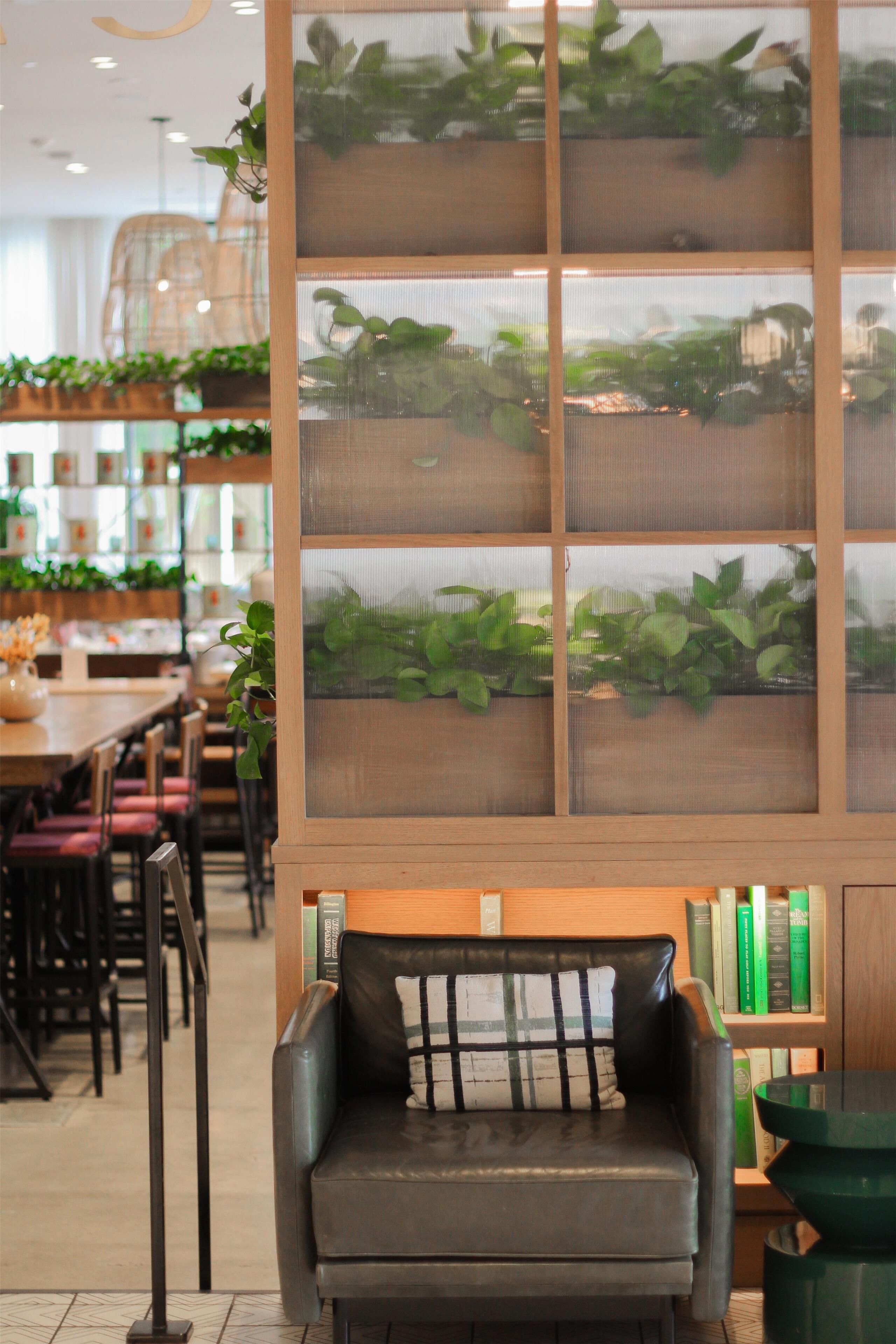 A seating area with a cushioned bench, a wooden bookshelf, and a plant display.