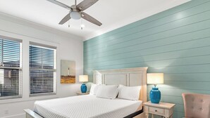 A bedroom with a bed, two bedside tables with lamps, a chair, a ceiling fan, and a window with blinds. - 😎 Night Heron, East. ⭐️⭐️⭐️⭐️⭐️ 6BR. Heated Pool. Beachview. Gorgeous! (Gulf Shores)
