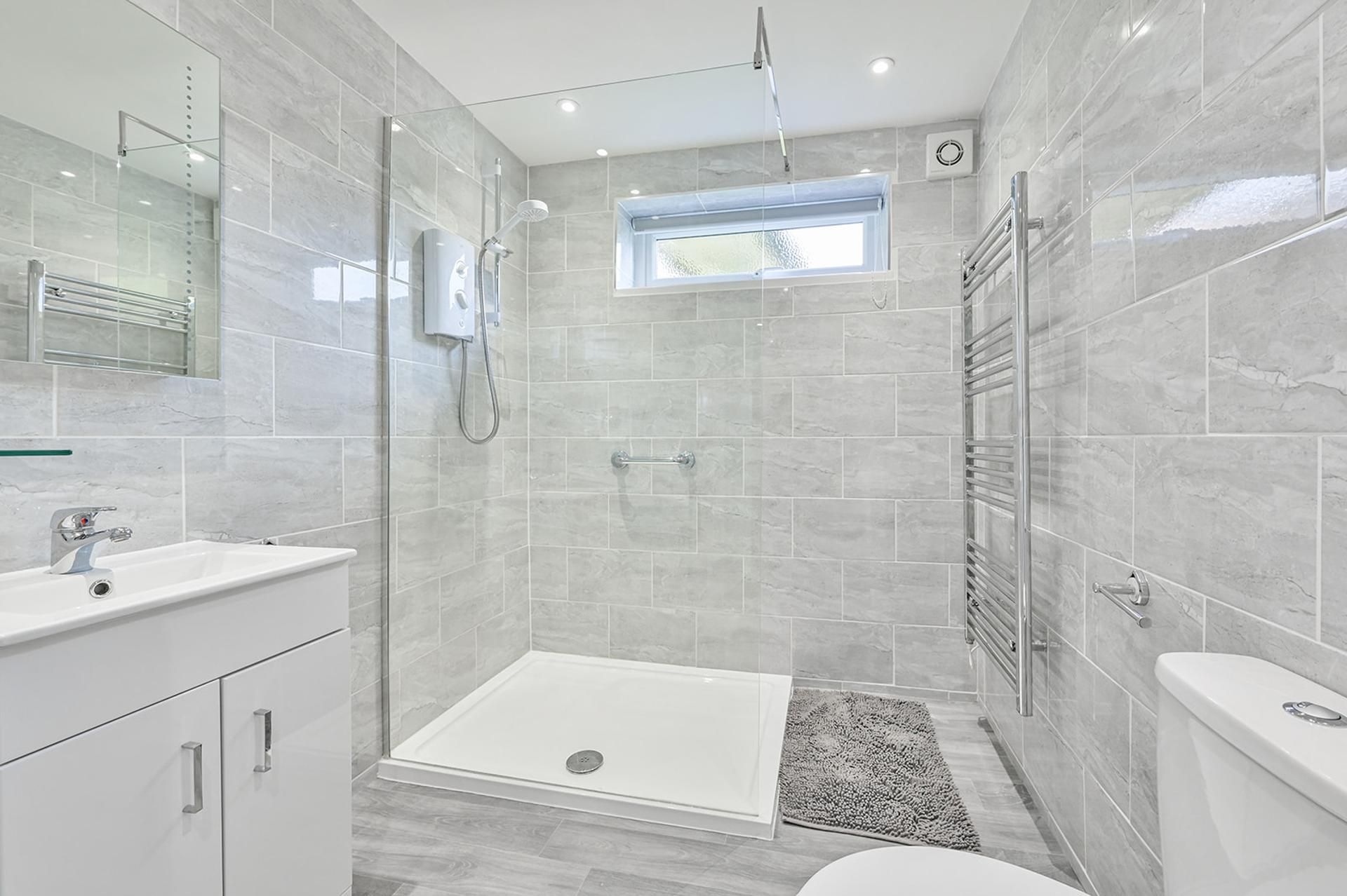 A modern bathroom with a glass-enclosed shower, a vanity with a sink, and a toilet.