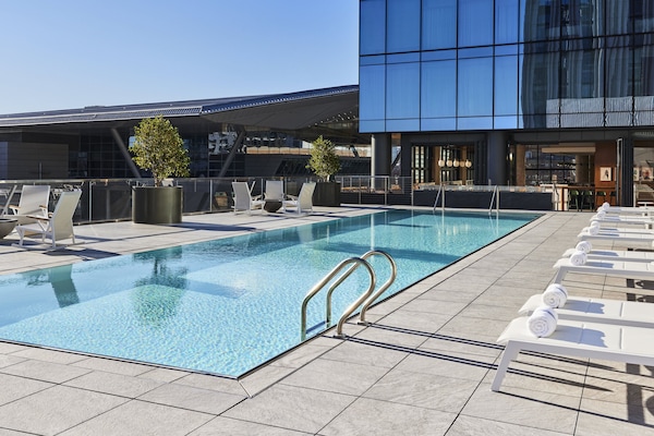 Een buitenzwembad, ligstoelen bij het zwembad