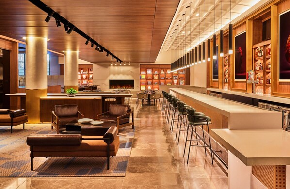 A modern hotel lobby with a bar area, seating arrangements, and a fireplace. - Omni Boston Hotel at the Seaport (Boston)