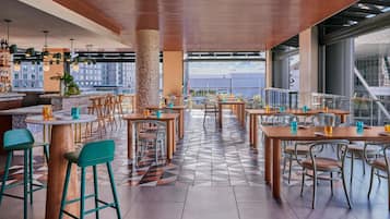 A modern restaurant with a high ceiling, wooden accents, and a patterned tile floor.